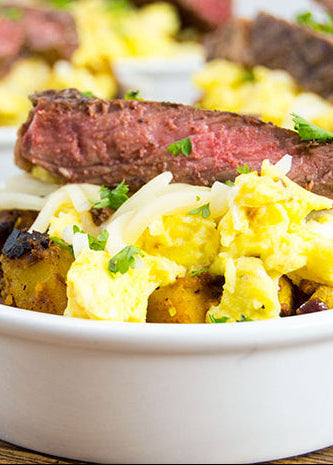 Close-up of a dish with steak, scrambled eggs, and potatoes.